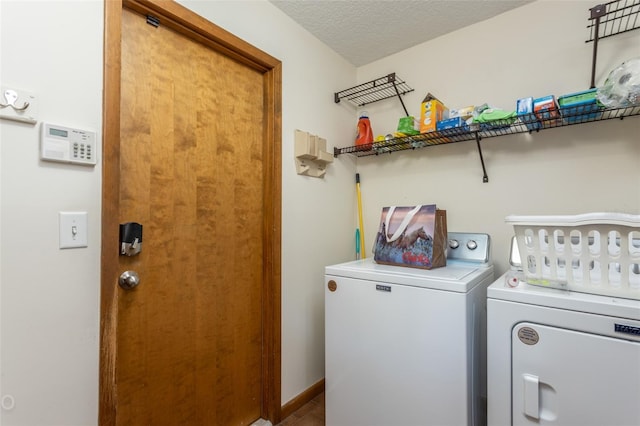 laundry area with independent washer and dryer and a textured ceiling