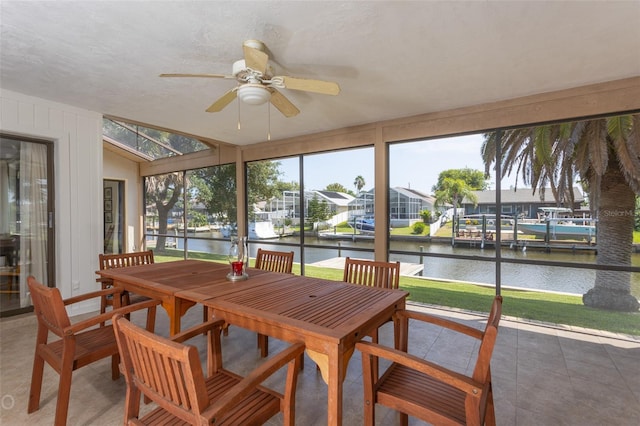 sunroom with ceiling fan and a water view