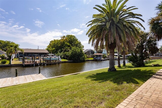 view of dock with a water view and a lawn