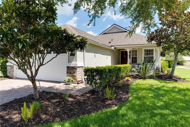 view of front of property with decorative driveway, roof with shingles, stucco siding, an attached garage, and a front yard