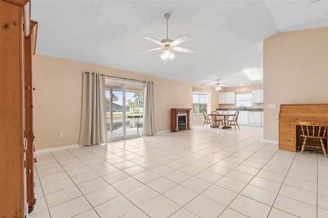 unfurnished living room with sink, ceiling fan, vaulted ceiling, and light tile patterned floors