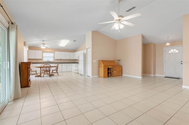 unfurnished living room featuring vaulted ceiling, sink, light tile patterned floors, and ceiling fan