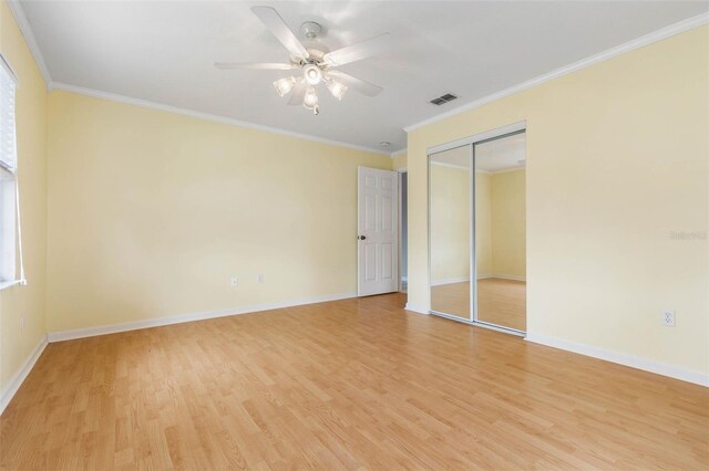 unfurnished bedroom featuring light wood-type flooring, ceiling fan, ornamental molding, and a closet