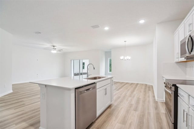 kitchen featuring appliances with stainless steel finishes, light wood-type flooring, sink, a center island with sink, and white cabinetry