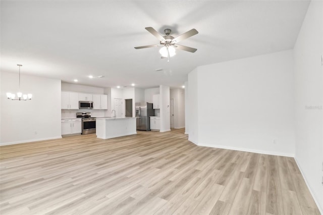 unfurnished living room with ceiling fan with notable chandelier, light hardwood / wood-style floors, and sink