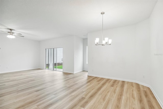 unfurnished room featuring ceiling fan with notable chandelier and light hardwood / wood-style floors