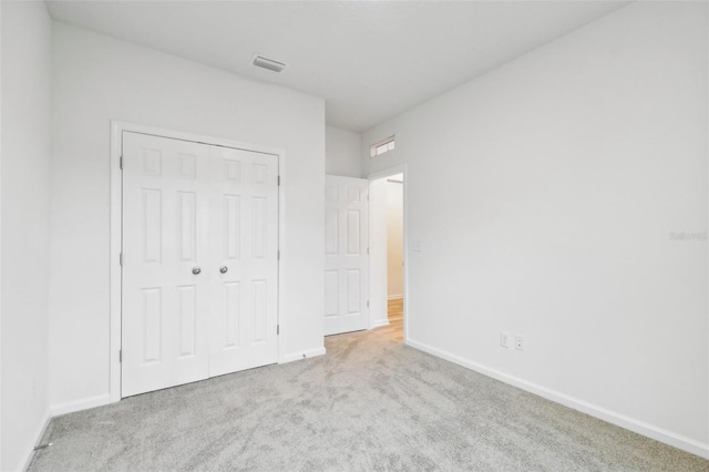 unfurnished bedroom with light carpet and a closet