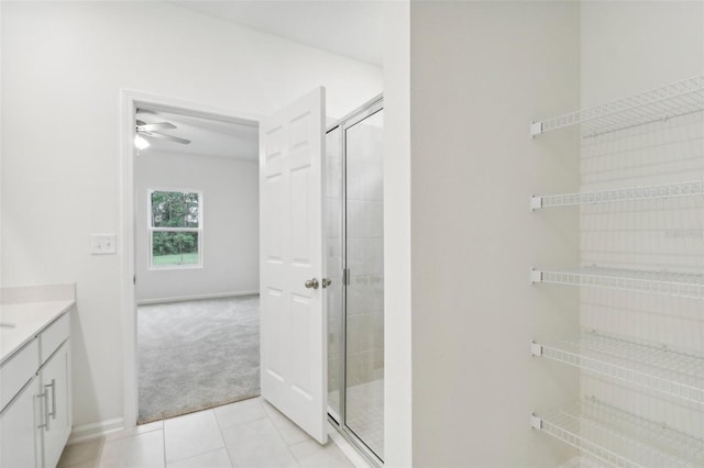 bathroom featuring tile patterned floors, ceiling fan, a shower with shower door, and vanity