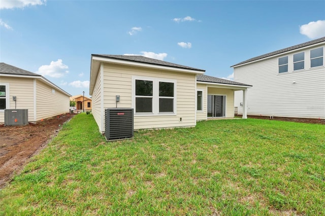 rear view of property with cooling unit and a lawn