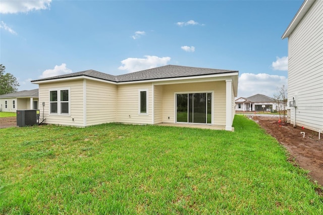 back of property with a yard and central AC