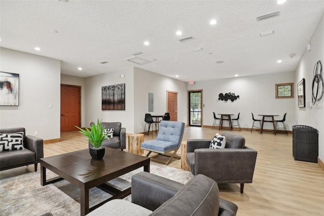 living room with light wood-type flooring, a textured ceiling, and electric panel