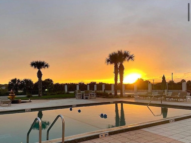 pool at dusk featuring a patio area