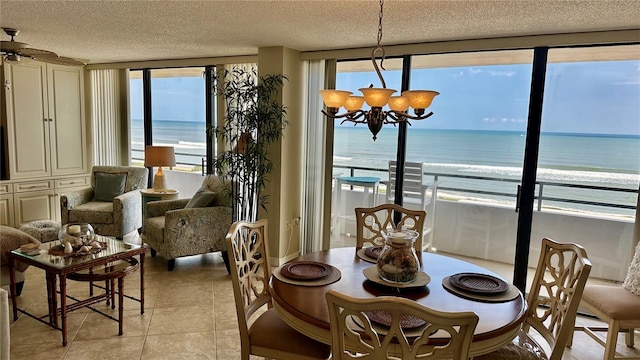 dining space featuring light tile patterned floors, an inviting chandelier, a textured ceiling, and a water view