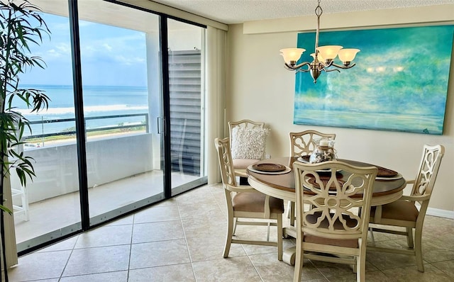 tiled dining space featuring a chandelier, a wall of windows, a textured ceiling, and a water view