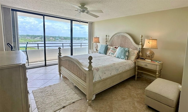 bedroom featuring light tile patterned floors, a textured ceiling, and a water view