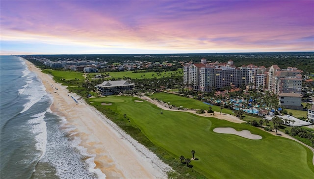 aerial view at dusk featuring a view of the beach and a water view