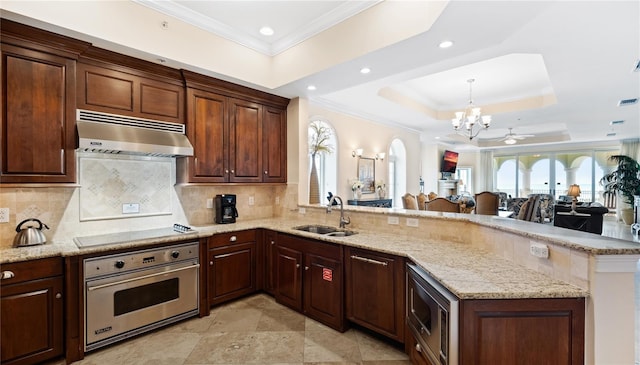 kitchen with sink, tasteful backsplash, a tray ceiling, light tile patterned floors, and stainless steel appliances