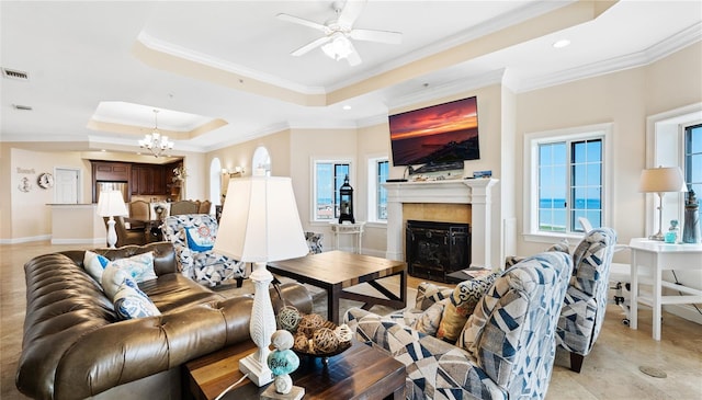 living room with a tray ceiling, crown molding, ceiling fan with notable chandelier, and light tile patterned floors