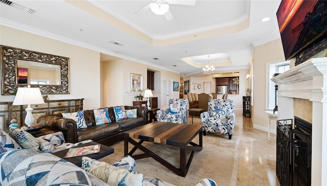 living room with a tray ceiling, ornamental molding, ceiling fan with notable chandelier, and light tile patterned floors