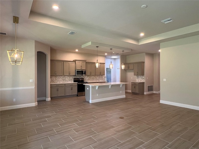 201 Hawthorn Ave, Palm Coast, FL 32164 - kitchen with stainless steel appliances, decorative backsplash, a kitchen bar, a tray ceiling, and recessed lighting
