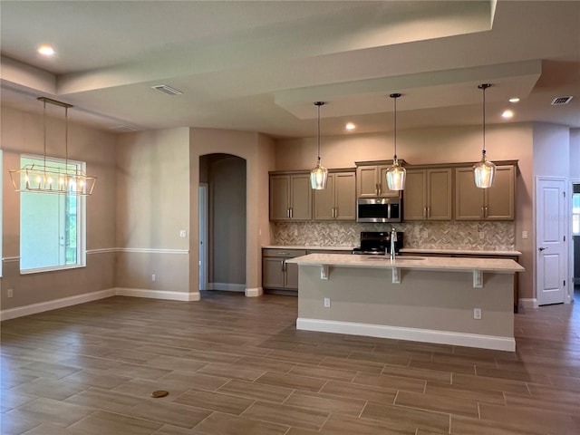201 Hawthorn Ave, Palm Coast, FL 32164 - kitchen featuring stainless steel microwave, arched walkways, a sink, decorative backsplash, and light countertops