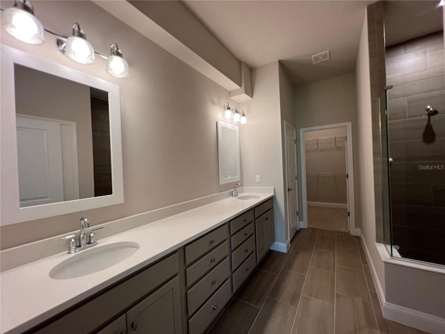 201 Hawthorn Ave, Palm Coast, FL 32164 - bathroom featuring a tile shower, double vanity, a walk in closet, and baseboards