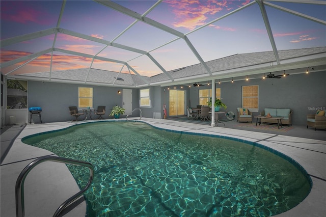 pool at dusk with a lanai, a patio, and ceiling fan