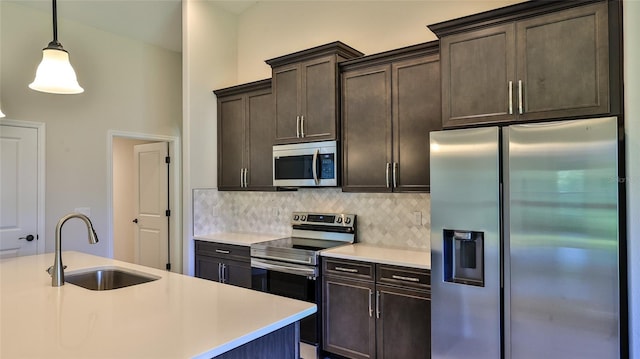 kitchen with appliances with stainless steel finishes, pendant lighting, tasteful backsplash, sink, and dark brown cabinetry