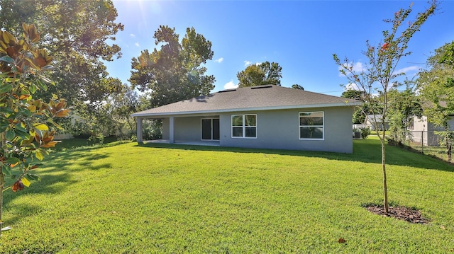 back of house with a patio and a lawn