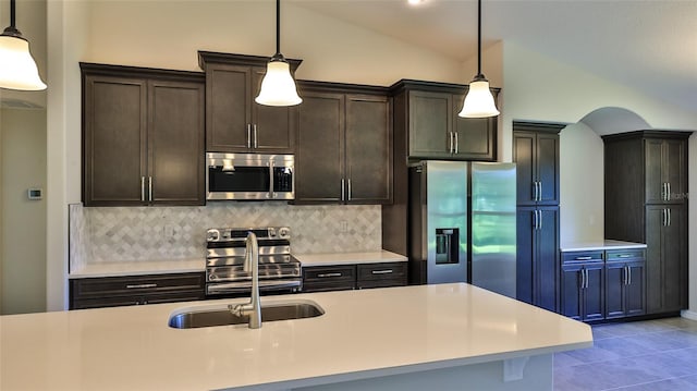 kitchen with appliances with stainless steel finishes, pendant lighting, lofted ceiling, decorative backsplash, and dark brown cabinetry