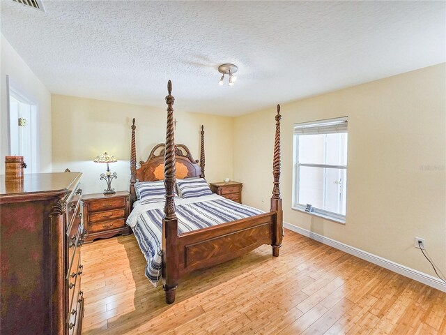 bedroom with a textured ceiling and light wood-type flooring