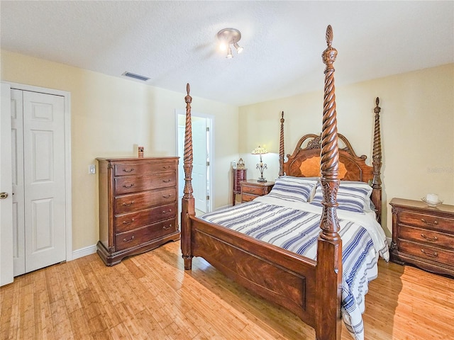 bedroom with a textured ceiling, light wood-type flooring, and a closet