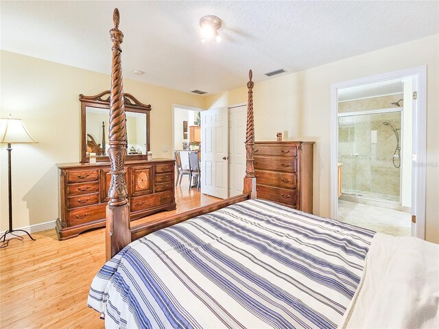 bedroom featuring light hardwood / wood-style flooring, ensuite bath, a textured ceiling, and a closet