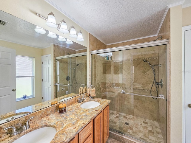 bathroom with vanity, ornamental molding, a textured ceiling, and a shower with shower door