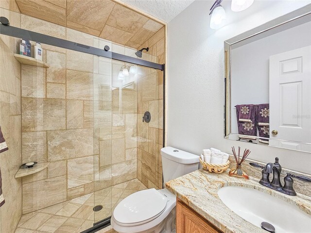 bathroom with an enclosed shower, vanity, and toilet