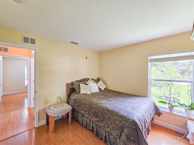 bedroom with hardwood / wood-style floors and a textured ceiling