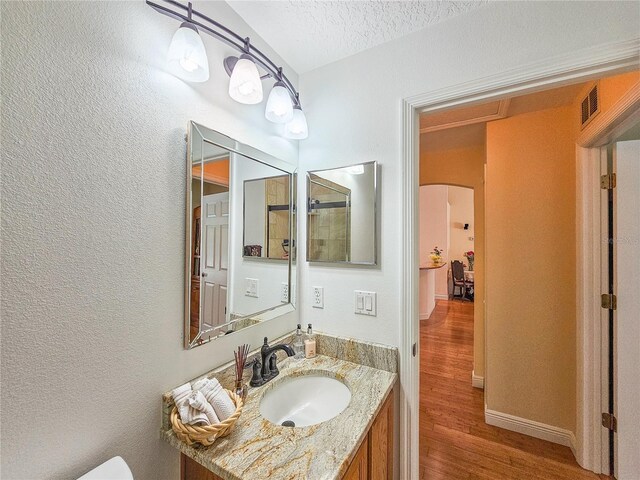 bathroom featuring a textured ceiling, wood-type flooring, and vanity