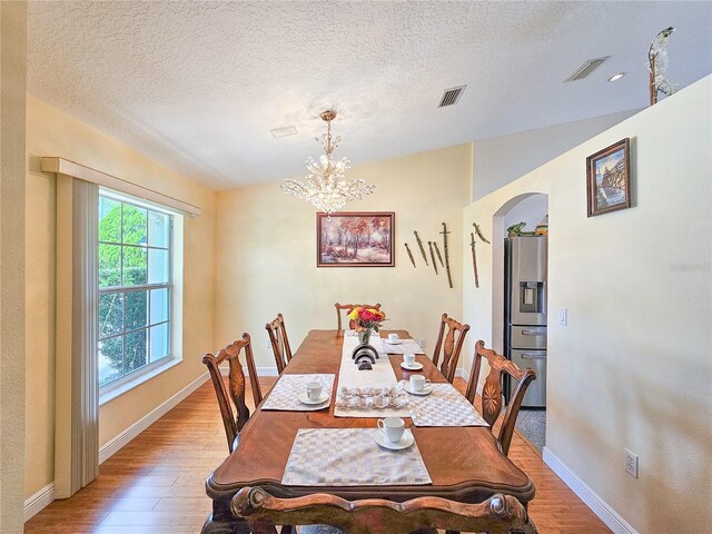 dining area with hardwood / wood-style floors, a textured ceiling, and a chandelier