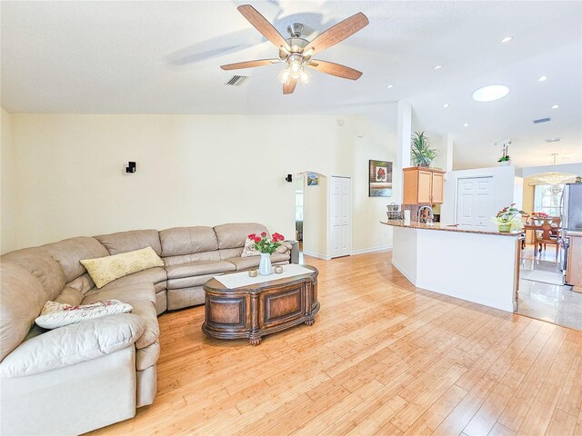 living room with ceiling fan, sink, light wood-type flooring, and high vaulted ceiling