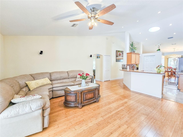 living room with vaulted ceiling, ceiling fan, sink, and light hardwood / wood-style floors