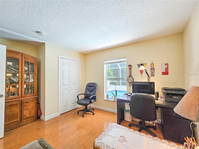 office space featuring light wood-type flooring and a textured ceiling