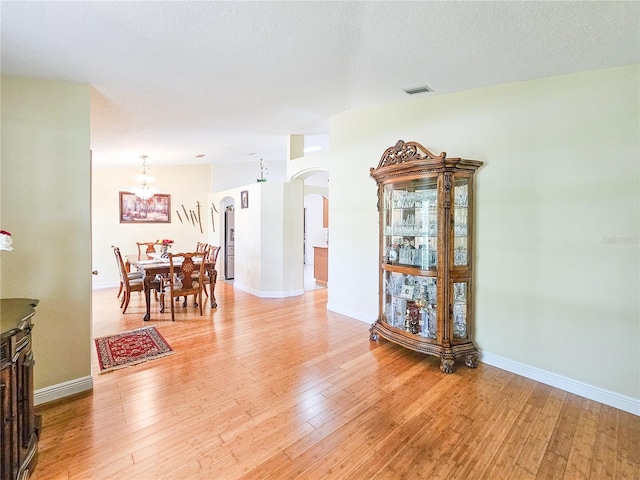 interior space with a textured ceiling, an inviting chandelier, and light hardwood / wood-style floors