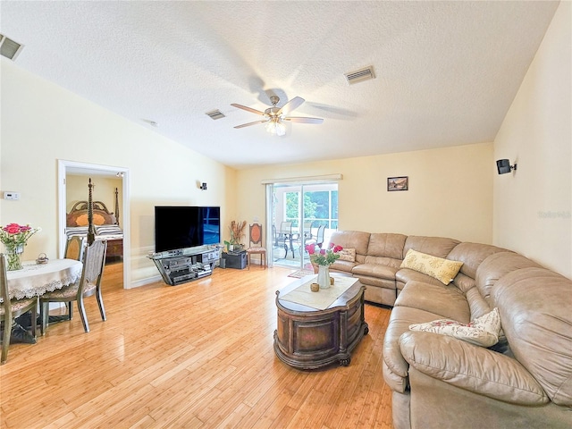 living room featuring ceiling fan, a textured ceiling, lofted ceiling, and light hardwood / wood-style floors