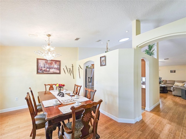 dining space with lofted ceiling, light hardwood / wood-style floors, and a chandelier