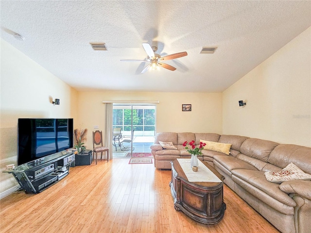 living room with hardwood / wood-style flooring, ceiling fan, and a textured ceiling