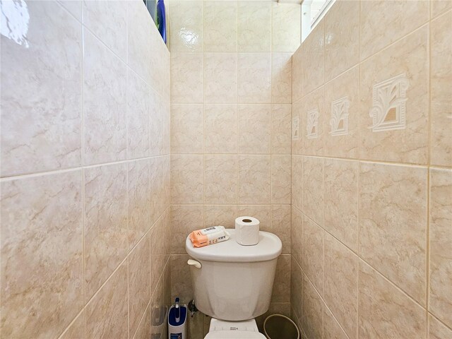 bathroom featuring tile walls and toilet