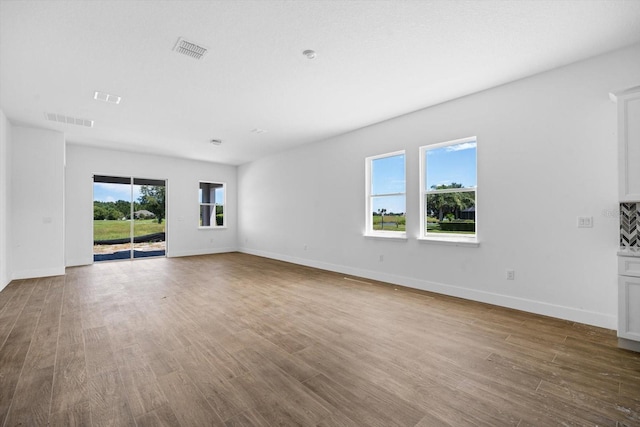 unfurnished living room featuring a healthy amount of sunlight and hardwood / wood-style floors