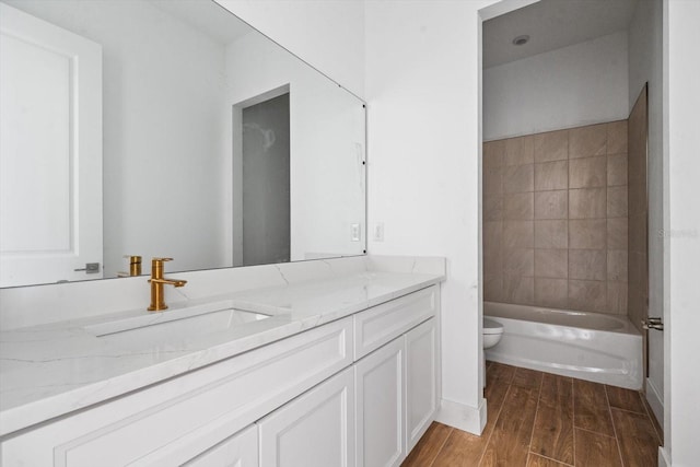 full bathroom with tiled shower / bath, vanity, toilet, and hardwood / wood-style flooring