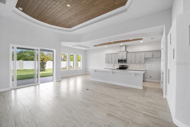 unfurnished living room with a tray ceiling, light tile patterned floors, and wood ceiling