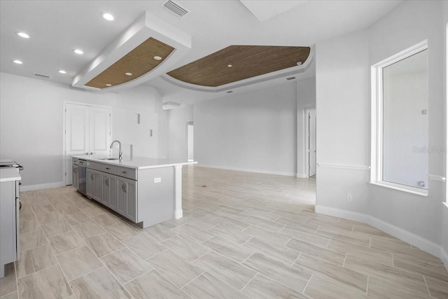 kitchen with stainless steel dishwasher, a kitchen island with sink, gray cabinetry, light tile patterned floors, and sink